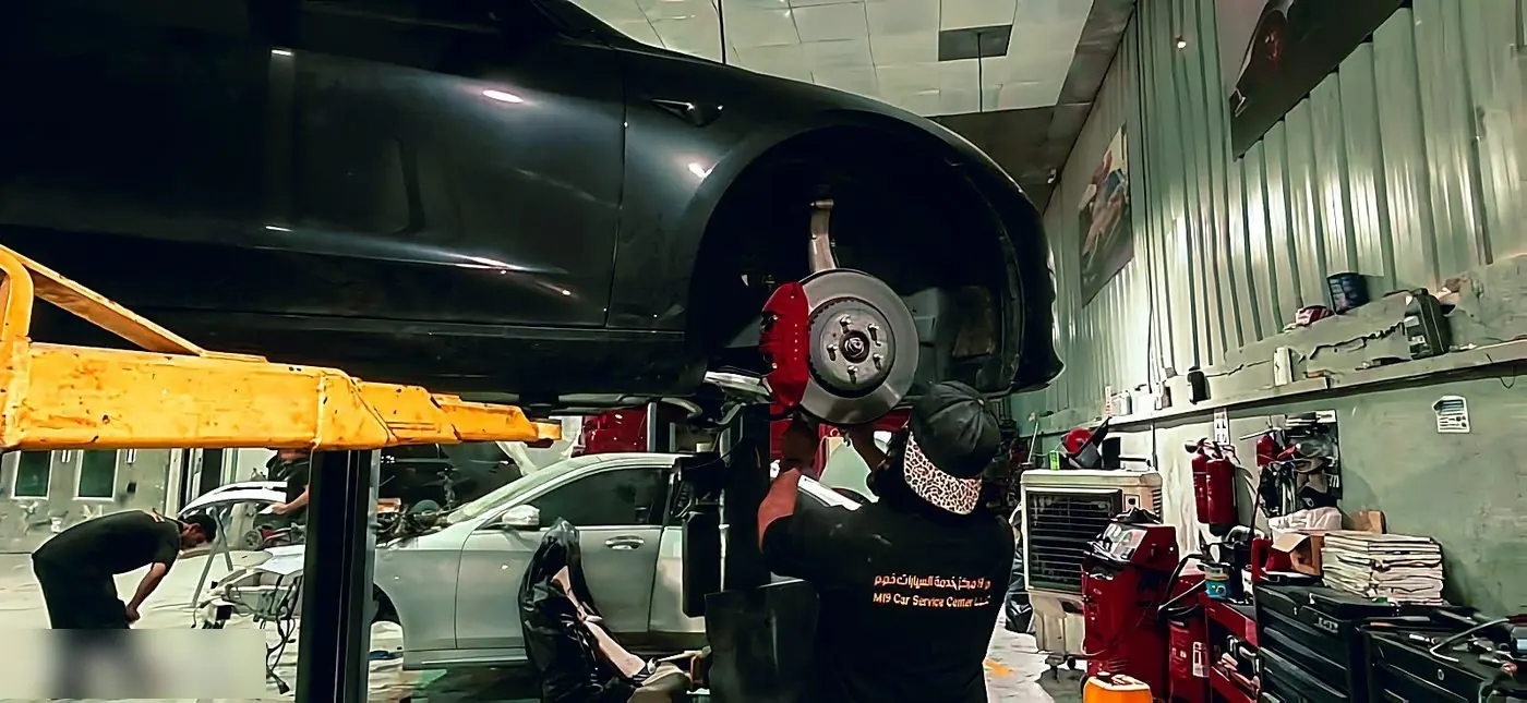 Technician working on the front brakes of a lifted car