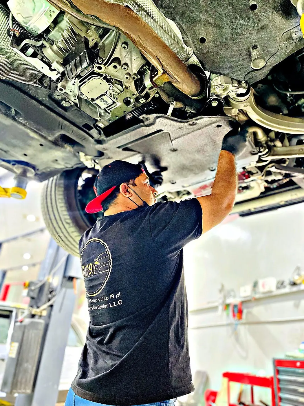 Technician inspecting the underside of a car on a lift